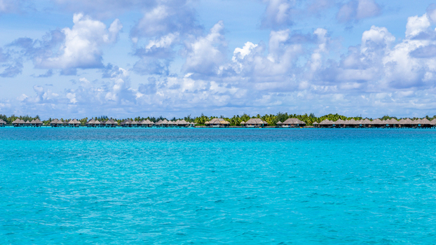 View of overwater bungalows in the turquoise lagoon of Bora Bora Leeward Islands French Polynesia.