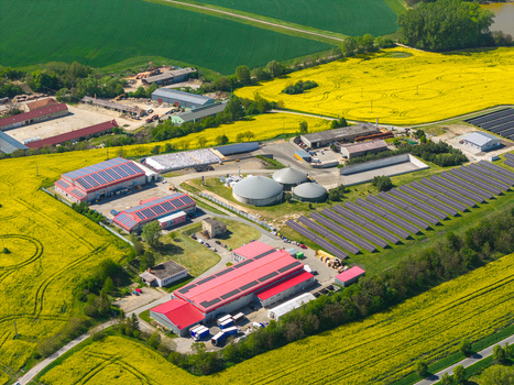 Aerial view of an industrial agricultural facility with solar panels biogas tanks and red roofed buildings surrounded by yellow rapeseed fields in Brno South Moravian Region Czechia.