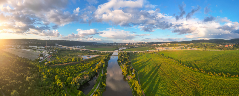 Aerial view of Lahovicky most spanning the river surrounded by lush green fields trees and a highway under a dramatic sunset sky in Prague Hlavni mesto Praha Czechia. Aerial view of Lahovicky most spanning the river surrounded by lush green fields trees and a highway under a dramatic sunset sky in Prague Hlavni mesto Praha Czechia.