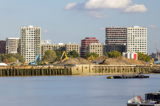 View of construction site with excavators and modern residential buildings along the River Thames in Greenwich London England United Kingdom. View of construction site with excavators and modern residential buildings along the River Thames in Greenwich London England United Kingdom.