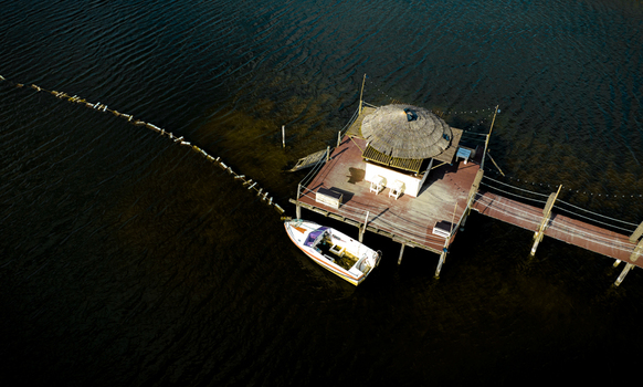 Aerial view of a wooden hut on stilts and a small boat moored at the Salinas de Aveiro salt pans over dark water in Aveiro Portugal. Aerial view of a wooden hut on stilts and a small boat moored at the Salinas de Aveiro salt pans over dark water in Aveiro Portugal.