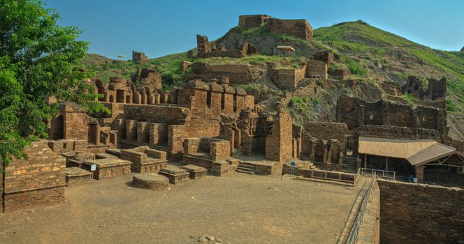 View of the ancient Buddhist ruins of Takht i Bahi with stone walls and structures built into the hillside in Takht Bhai Khyber Pakhtunkhwa Pakistan.