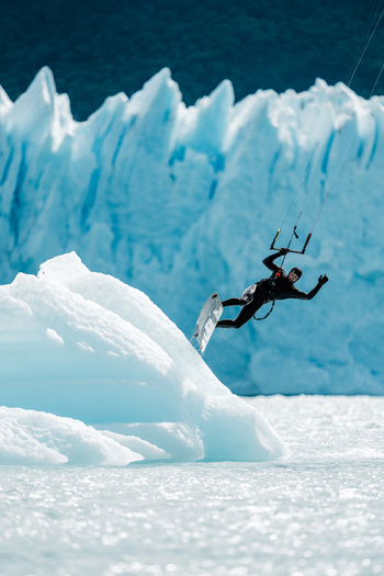 View of a kitesurfer performing a jump in front of the massive blue ice walls of the Perito Moreno glacier in Perito Moreno Santa Cruz Province Argentina. View of a kitesurfer performing a jump in front of the massive blue ice walls of the Perito Moreno glacier in Perito Moreno Santa Cruz Province Argentina.
