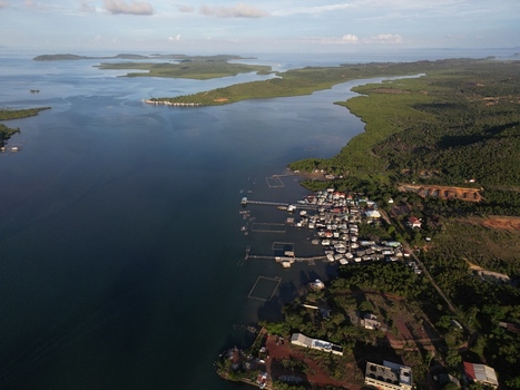 Aerial view of the coastal village of Galang Baru with stilt houses and fish farms along the lush shoreline of Galang Riau Islands Indonesia. Aerial view of the coastal village of Galang Baru with stilt houses and fish farms along the lush shoreline of Galang Riau Islands Indonesia.