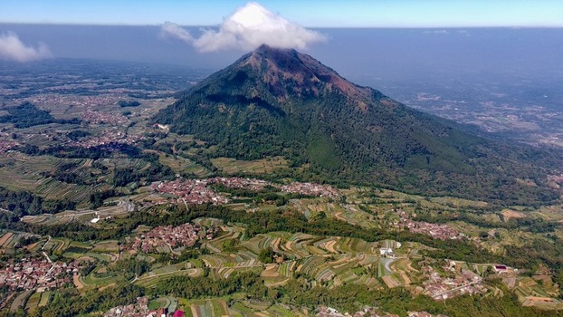 Aerial view of Mount Andong rising above terraced agricultural fields and rural villages in the lush landscape of Ngablak Central Java Indonesia.