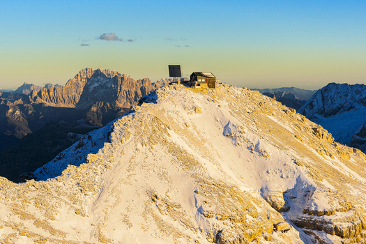 Aerial view of a snow covered mountain peak with a small building on top of Piz Bo&egrave; under a clear sky Dolomites Italy.