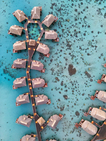 Aerial view of overwater bungalows at Sofitel Kia Ora Moorea Beach Resort with wooden walkways over the turquoise lagoon and coral reefs in Moorea Maiao Windward Islands French Polynesia. Aerial view of overwater bungalows at Sofitel Kia Ora Moorea Beach Resort with wooden walkways over the turquoise lagoon and coral reefs in Moorea Maiao Windward Islands French Polynesia.