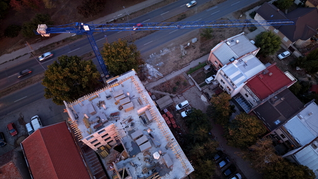 Aerial view of a construction site featuring a blue tower crane concrete structures and surrounding residential houses with red roofs in Pancevo Vojvodina Serbia.