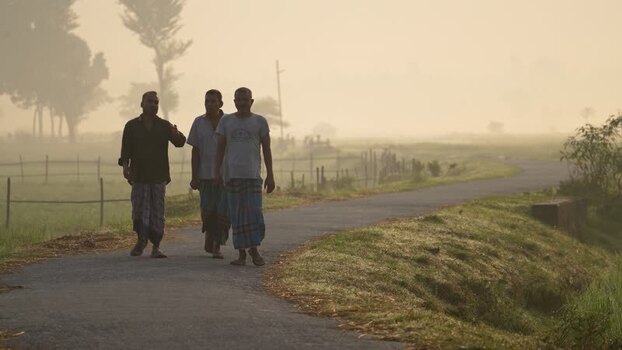 View of three men walking on a rural road in Bogura Bangladesh.