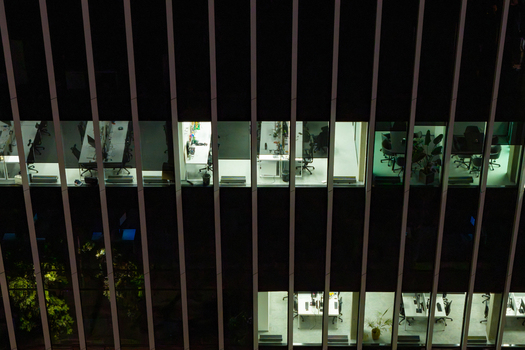 Aerial view of a modern office building facade at night with illuminated workspaces and vertical architectural lines in the financial center of Warsaw Masovian Voivodeship Poland.