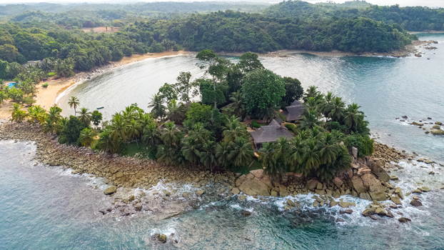 Axim Western Region Ghana 09 February 2023 Aerial view of Lou Moon Resort nestled on a lush peninsula with palm trees rocky shores and sandy beaches along the Atlantic coast. Axim Western Region Ghana 09 February 2023 Aerial view of Lou Moon Resort nestled on a lush peninsula with palm trees rocky shores and sandy beaches along the Atlantic coast.