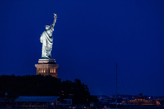 New York New York United States 08 July 2021 View of the Statue of Liberty illuminated against a deep blue night sky with harbor waters in the foreground. New York New York United States 08 July 2021 View of the Statue of Liberty illuminated against a deep blue night sky with harbor waters in the foreground.