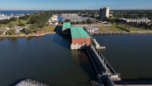 Aerial view of the Lake Pontchartrain shoreline featuring a pumping station with green roofs a marina and calm water in Jefferson Parish Louisiana United States.