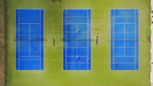 Aerial view of three blue tennis courts with people playing Czechia. Aerial view of three blue tennis courts with people playing Czechia.