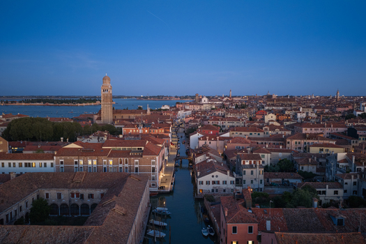 Aerial view of the historic city of Venice with its iconic canals terracotta rooftops and the San Giorgio Maggiore campanile under a clear twilight sky in Venice Veneto Italy. Aerial view of the historic city of Venice with its iconic canals terracotta rooftops and the San Giorgio Maggiore campanile under a clear twilight sky in Venice Veneto Italy.
