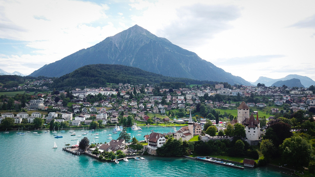 Aerial view of Schloss Spiez and the town waterfront on Lake Thun with the Niesen mountain peak under a cloudy sky Spiez Bern Switzerland. Aerial view of Schloss Spiez and the town waterfront on Lake Thun with the Niesen mountain peak under a cloudy sky Spiez Bern Switzerland.