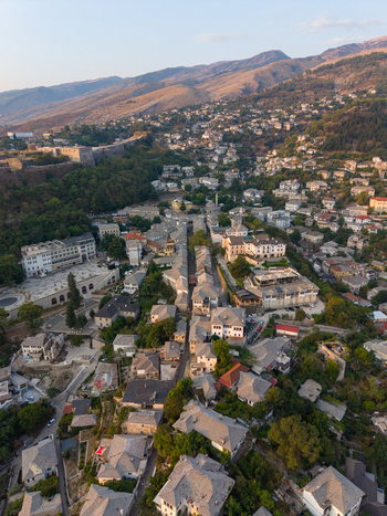 Aerial view of the historic stone city of Gjirokaster featuring traditional Ottoman style houses with slate roofs and the prominent castle in Gjirokaster Gjirokaster County Albania. Aerial view of the historic stone city of Gjirokaster featuring traditional Ottoman style houses with slate roofs and the prominent castle in Gjirokaster Gjirokaster County Albania.