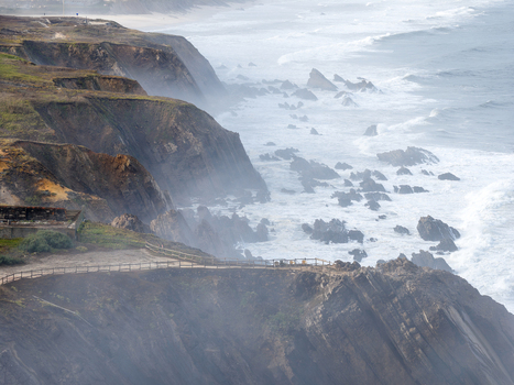 Aerial view of the rugged cliffs of Farol Penedo da Saudade with crashing waves against rocky outcrops and a misty coastal path Marinha Grande Leiria Portugal. Aerial view of the rugged cliffs of Farol Penedo da Saudade with crashing waves against rocky outcrops and a misty coastal path Marinha Grande Leiria Portugal.