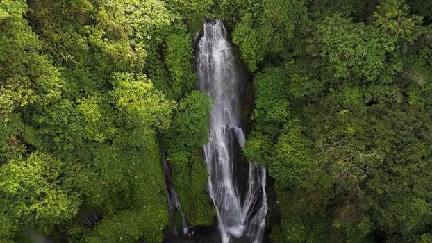 Aerial view of cascading waterfall in lush jungle Indonesia.