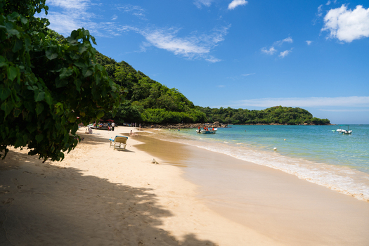 View of Jungle Beach with golden sand turquoise water and lush tropical vegetation under a blue sky in Unawatuna Southern Province Sri Lanka.