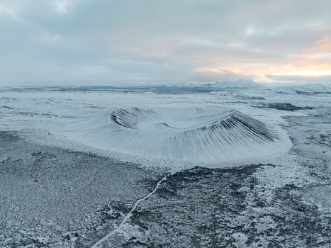 Aerial view of Hverfjall volcano crater surrounded by snow covered volcanic terrain under a cloudy sky in Thingeyjarsveit Iceland. Aerial view of Hverfjall volcano crater surrounded by snow covered volcanic terrain under a cloudy sky in Thingeyjarsveit Iceland.