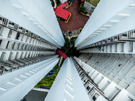 Aerial view of tall residential apartment buildings with white balconies and a small courtyard below in Singapore Singapore. Aerial view of tall residential apartment buildings with white balconies and a small courtyard below in Singapore Singapore.