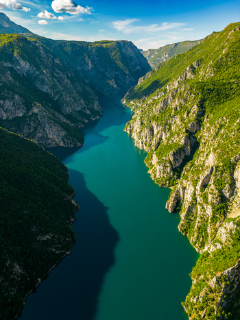 Aerial view of Piva Lake surrounded by steep rocky canyon walls and lush green vegetation in Pluzine Municipality Montenegro. Aerial view of Piva Lake surrounded by steep rocky canyon walls and lush green vegetation in Pluzine Municipality Montenegro.