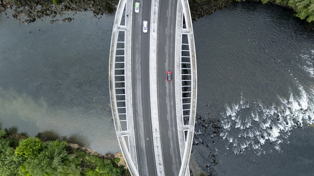 Aerial view of the modern Ponte do Milenio bridge with cars driving over the Minho River and lush green banks in Orense Ourense Spain. Aerial view of the modern Ponte do Milenio bridge with cars driving over the Minho River and lush green banks in Orense Ourense Spain.