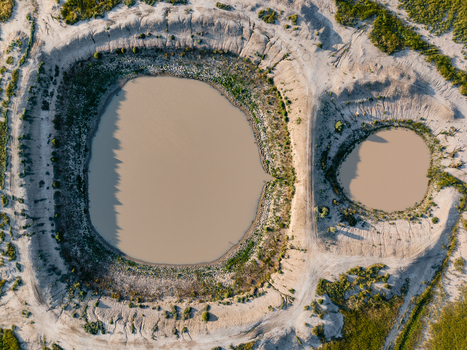 Aerial view of two circular ponds surrounded by arid flat landscape with sparse vegetation and dirt tracks in Hay New South Wales Australia.
