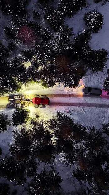 Aerial view of a tractor clearing snow in a forest Latvia.