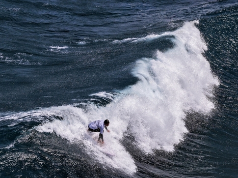 Aerial view of a surfer riding a powerful wave at Praia do Areal de Santa Barbara with white sea foam and deep blue water Ribeira Grande Azores Portugal. Aerial view of a surfer riding a powerful wave at Praia do Areal de Santa Barbara with white sea foam and deep blue water Ribeira Grande Azores Portugal.