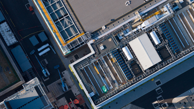Aerial view of the industrial rooftop of a large facility featuring complex cooling systems HVAC units and ventilation pipes in Longcross England United Kingdom.
