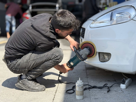 View of a man polishing the front bumper of a white car with a power buffer in an auto detailing shop Avcilar Istanbul Turkiye. View of a man polishing the front bumper of a white car with a power buffer in an auto detailing shop Avcilar Istanbul Turkiye.