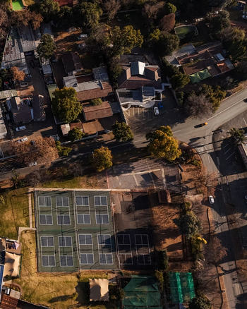 Aerial view of tennis courts surrounded by residential houses roads and trees in a suburban neighborhood of Johannesburg Gauteng South Africa.