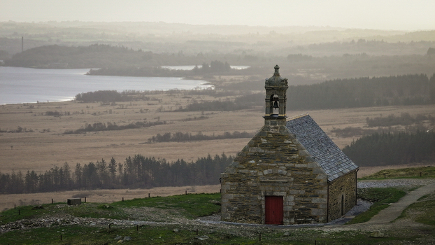 Aerial view of the historic Mont Saint Michel de Brasparts chapel overlooking a misty valley and distant lake in Saint Rivoal Bretagne France. Aerial view of the historic Mont Saint Michel de Brasparts chapel overlooking a misty valley and distant lake in Saint Rivoal Bretagne France.