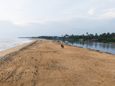 Aerial view of a sandy beach spit between the ocean and a lagoon with people walking and palm trees in Galle Southern Province Sri Lanka. Aerial view of a sandy beach spit between the ocean and a lagoon with people walking and palm trees in Galle Southern Province Sri Lanka.