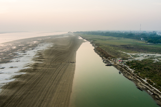Aerial view of the Padma River with sandy banks small boats and people along the shore in Rajshahi Rajshahi Division Bangladesh.