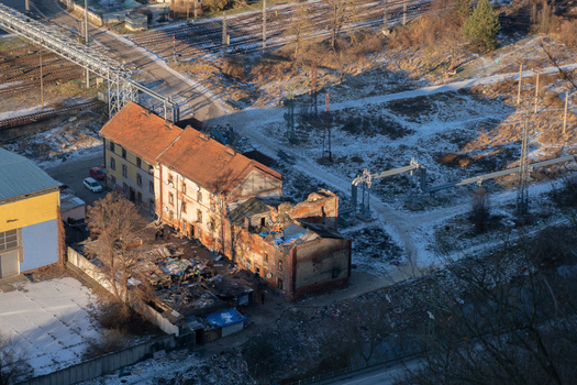 Aerial view of gipsy ghetto brick buildings with terracotta roofs sit nestled amidst patches of frost and stark shadows Balkan Banskobystricky kraj Slovakia. Aerial view of gipsy ghetto brick buildings with terracotta roofs sit nestled amidst patches of frost and stark shadows Balkan Banskobystricky kraj Slovakia.
