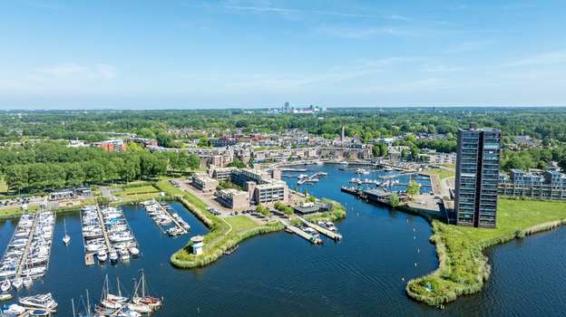 Aerial view of the marina in Almere with numerous boats docked modern residential buildings and lush green surroundings in Almere Flevoland Netherlands. Aerial view of the marina in Almere with numerous boats docked modern residential buildings and lush green surroundings in Almere Flevoland Netherlands.