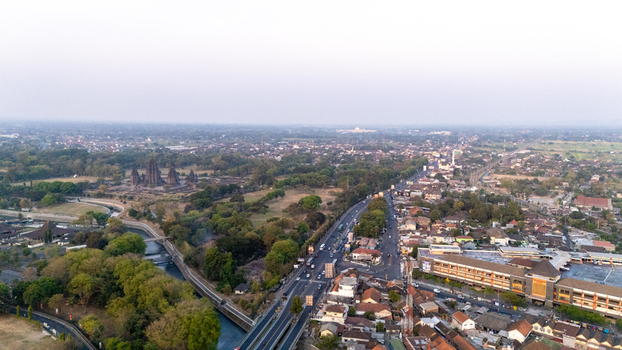 Aerial view of the ancient Prambanan Temple complex surrounded by lush greenery and urban development in Kecamatan Prambanan Daerah Istimewa Yogya Indonesia.