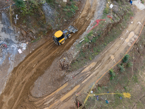 Aerial view of a yellow construction loader working on a muddy dirt road at a development site in Istanbul Istanbul Turkiye. Aerial view of a yellow construction loader working on a muddy dirt road at a development site in Istanbul Istanbul Turkiye.