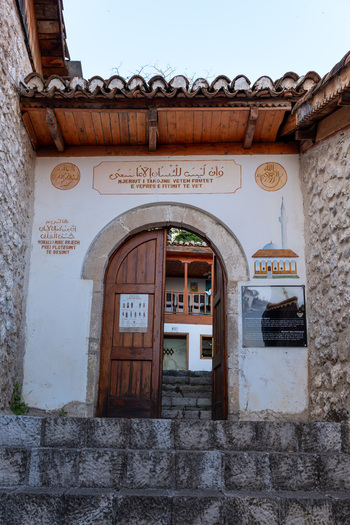 View of the historic stone entrance to the Dollma Tekke with traditional inscriptions and an open wooden door in Kruje Durres County Albania.