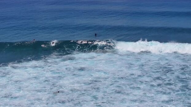 Aerial view of surfers riding a breaking wave in Thulusdhoo Maldives.