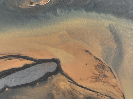 Aerial view of the river delta with swirling sediment patterns dark volcanic sandbanks and flowing water in Selfoss Sveitarfelagid Arborg Iceland. Aerial view of the river delta with swirling sediment patterns dark volcanic sandbanks and flowing water in Selfoss Sveitarfelagid Arborg Iceland.