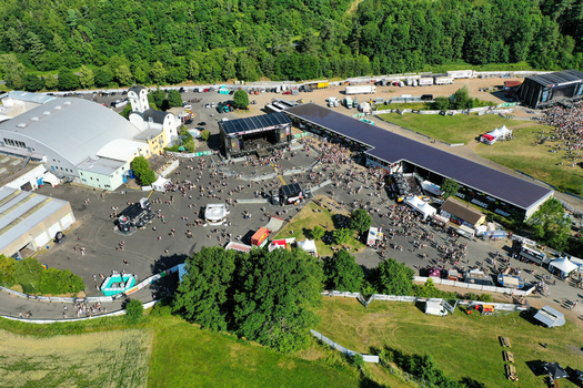 Geiselwind Germany 21 June 2025 Aerial view of Eventzentrum Strohofer Geiselwind musichall with outdoor stages crowds of people and lush green forest in the background. Geiselwind Germany 21 June 2025 Aerial view of Eventzentrum Strohofer Geiselwind musichall with outdoor stages crowds of people and lush green forest in the background.