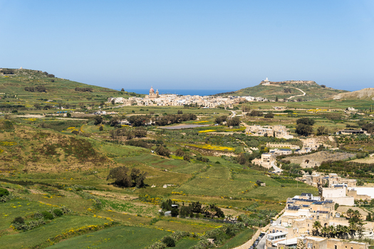 View of the town of Zebbug with its parish church dome overlooking terraced green fields and the Mediterranean Sea in Zebbug Gozo Region Malta. View of the town of Zebbug with its parish church dome overlooking terraced green fields and the Mediterranean Sea in Zebbug Gozo Region Malta.
