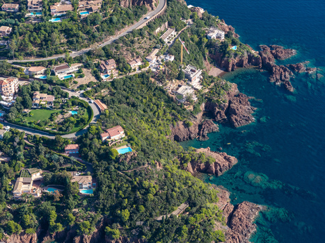 Aerial view of Le Trayas featuring luxury villas with swimming pools rugged red rock cliffs and the deep blue Mediterranean Sea in Saint Raphael Provence Alpes Cote d Azur France. Aerial view of Le Trayas featuring luxury villas with swimming pools rugged red rock cliffs and the deep blue Mediterranean Sea in Saint Raphael Provence Alpes Cote d Azur France.