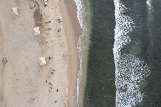 Aerial view of the sandy beach with umbrellas and people relaxing by the ocean waves in Sayulita Nayarit Mexico. Aerial view of the sandy beach with umbrellas and people relaxing by the ocean waves in Sayulita Nayarit Mexico.