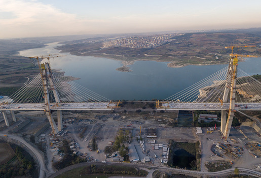 Aerial view of a large cable stayed bridge under construction spanning a wide reservoir with cranes concrete pillars and surrounding hilly landscape in Istanbul Istanbul Turkiye.