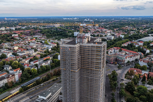 Aerial view of the Steglitzer Kreisel skyscraper under renovation surrounded by the urban cityscape with rooftops trees roads and a yellow construction crane Berlin Berlin Germany. Aerial view of the Steglitzer Kreisel skyscraper under renovation surrounded by the urban cityscape with rooftops trees roads and a yellow construction crane Berlin Berlin Germany.